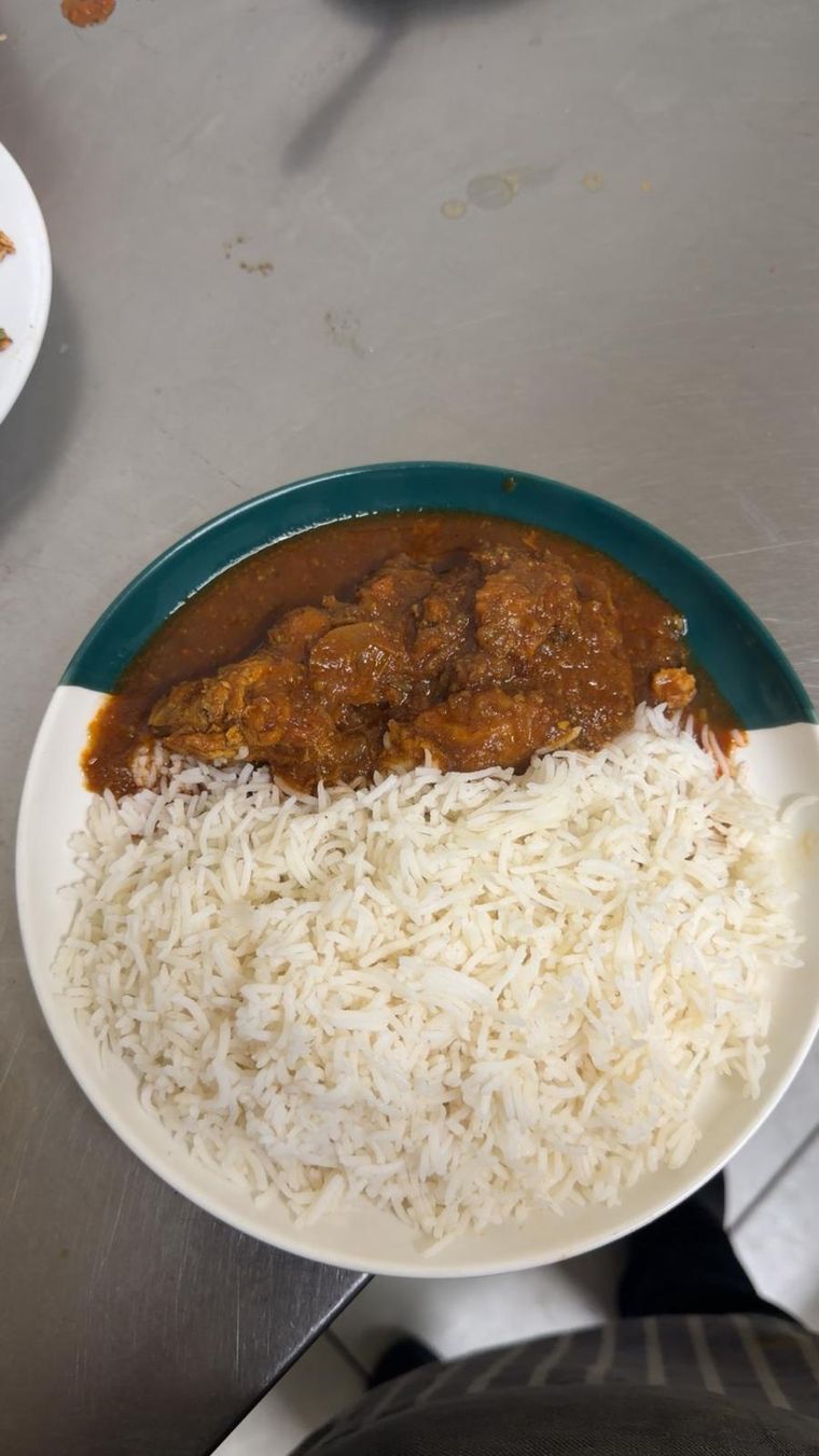 A plate of chicken curry served beside a mound of steamed basmati rice