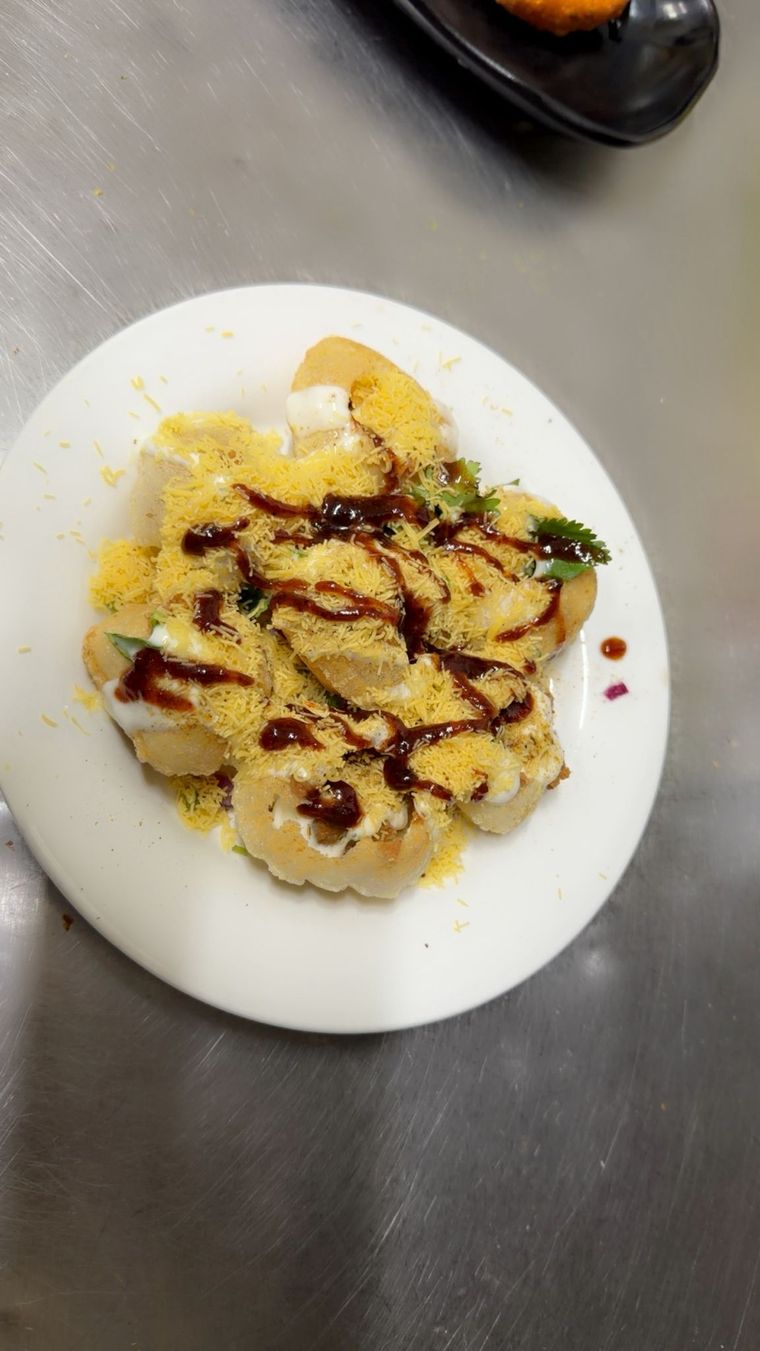 Plate of dahi puri drizzled with tamarind chutney and topped with sev