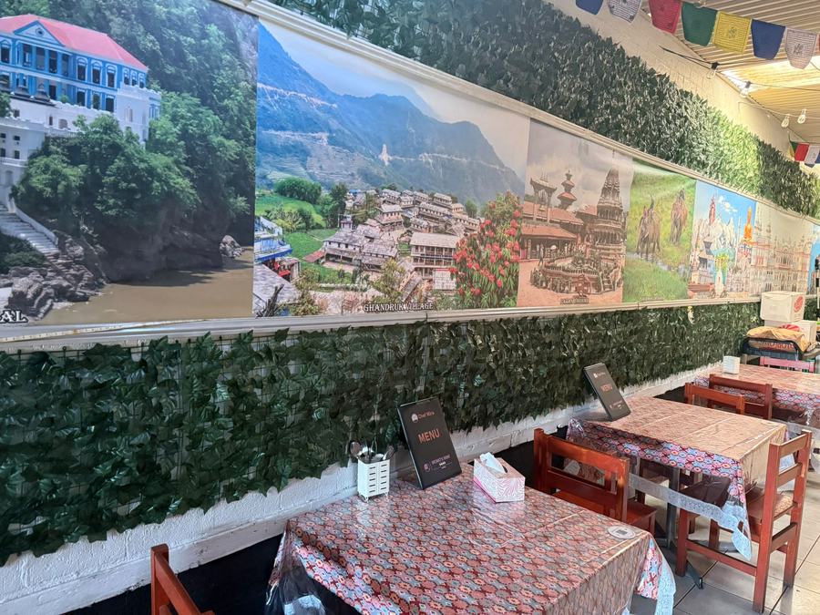 Photographs of Nepal — Ghandruk village, temples and mountains — along the courtyard wall